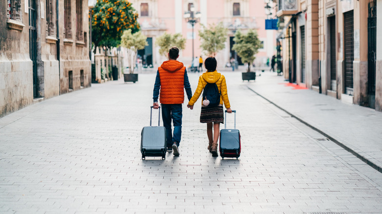 Couple rolling luggage European street