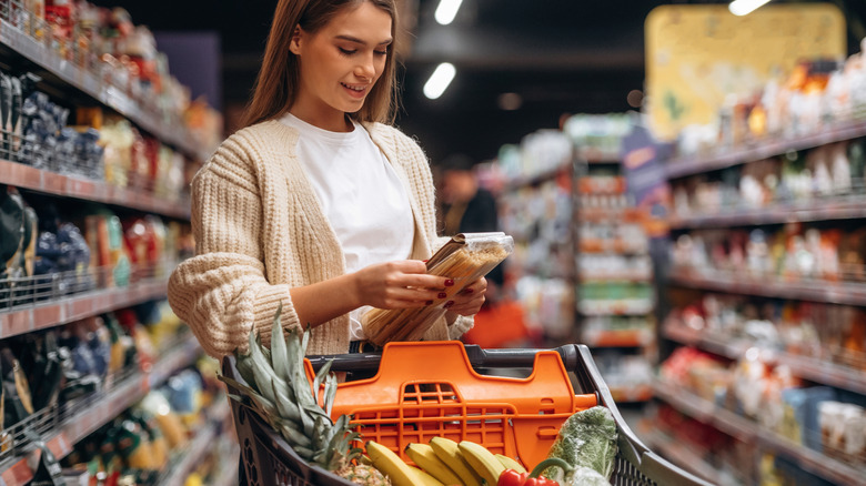 A woman with a full shopping cart in a supermarket.