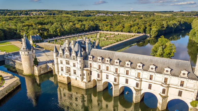 a view over the French Renaissance château of Chenonceau showing off the arched gallery reflected in the water below