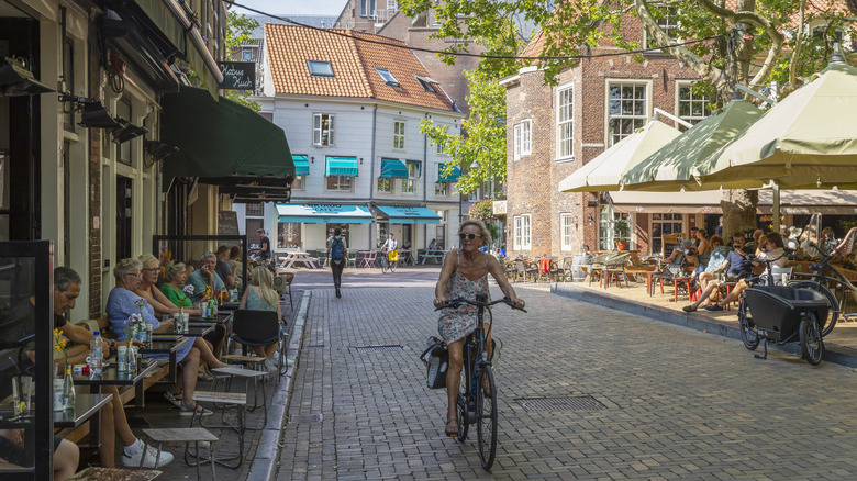 A woman rides her bicycle down a cobblestone street in Delft, Netherlands