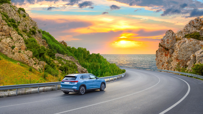 Car driving on European road with ocean and sunset in view