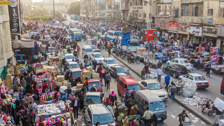 busy street with pedestrians, cars, merchants