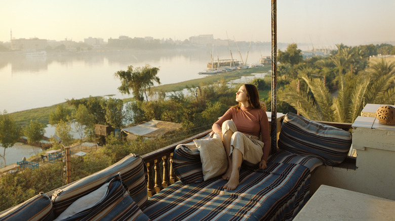 woman on balcony looking over greenery and river
