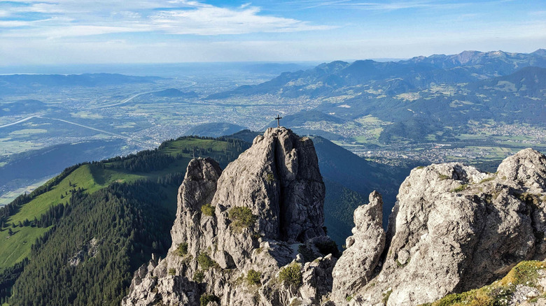 A mountain view with a cross on the peak and valleys in the background