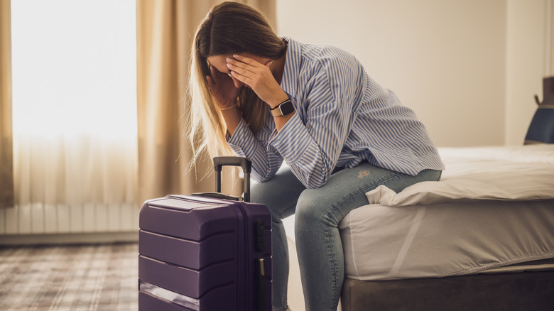 Tired tourist in a hotel room with head in her hands