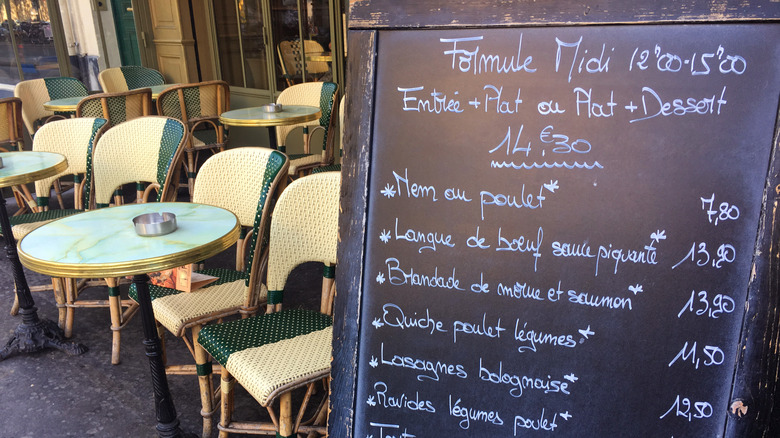 A sandwich board presents menu items in French