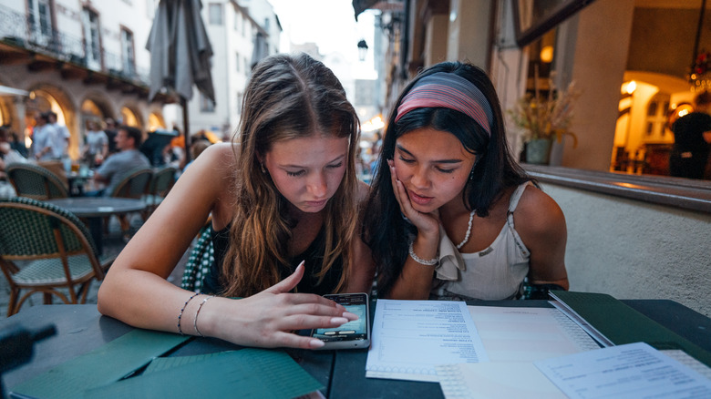 Two young travelers pore over a menu in a European restaurant