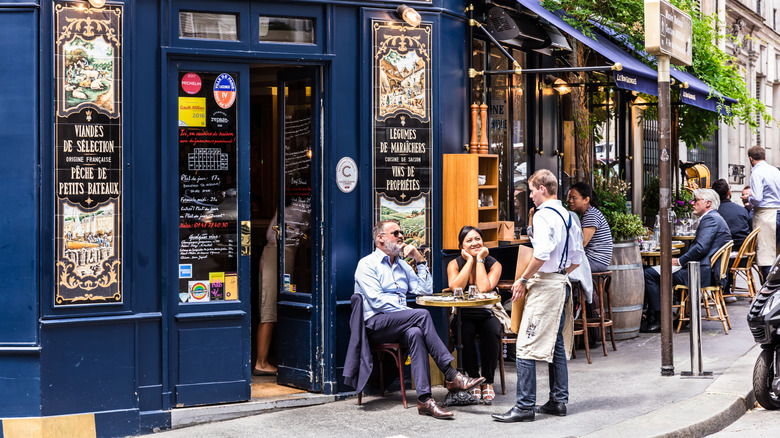 Server talking to customers at a corner cafe in Paris
