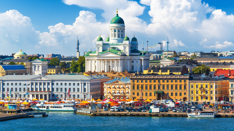 a shoreline filled with colored buildings with a large white church rising up behind