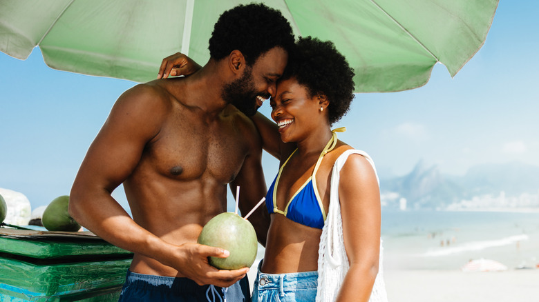 Couple embracing on beach under umbrella
