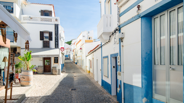 Narrow main cobbled street of Salema with blue and white houses