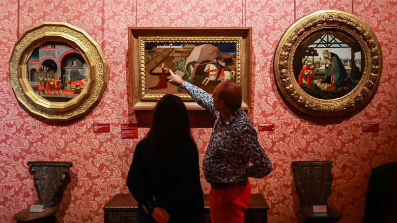 A person pointing at paintings in gilded frames at the Musée Jacquemart-André