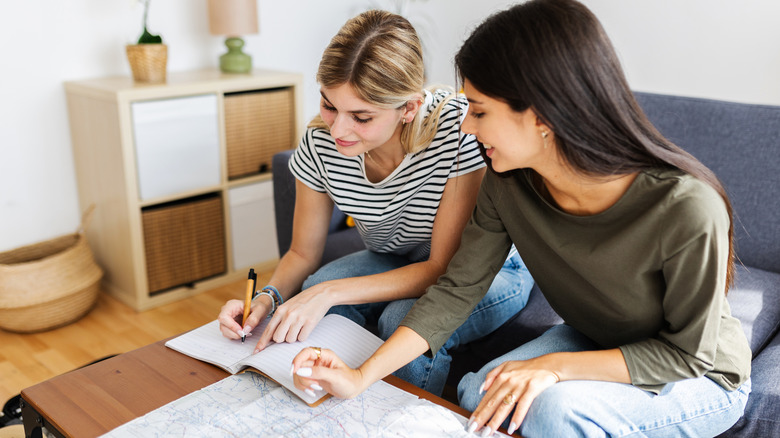 Two happy young girls planning their next vacation trip at home