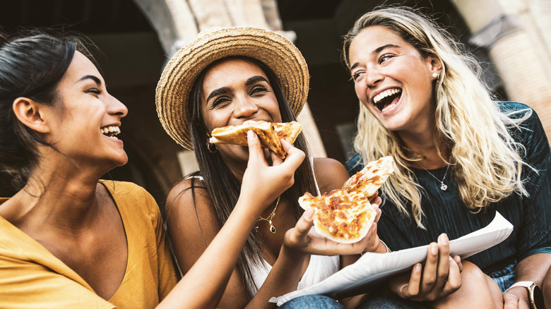 three women sharing pizza
