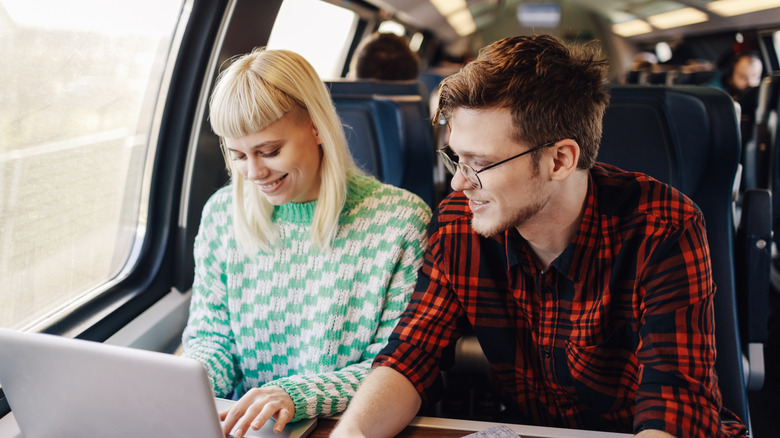 travelers using laptop on train