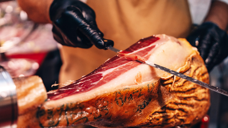 Vendor slicing jamon Iberico from a ham leg in a Spanish market