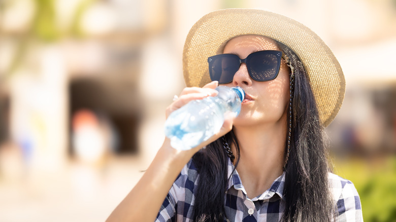 woman wearing sunhat drinking water