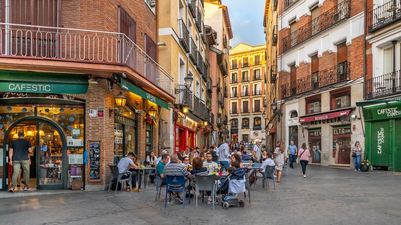 Pedestrian street and outdoor café tables with many people sitting