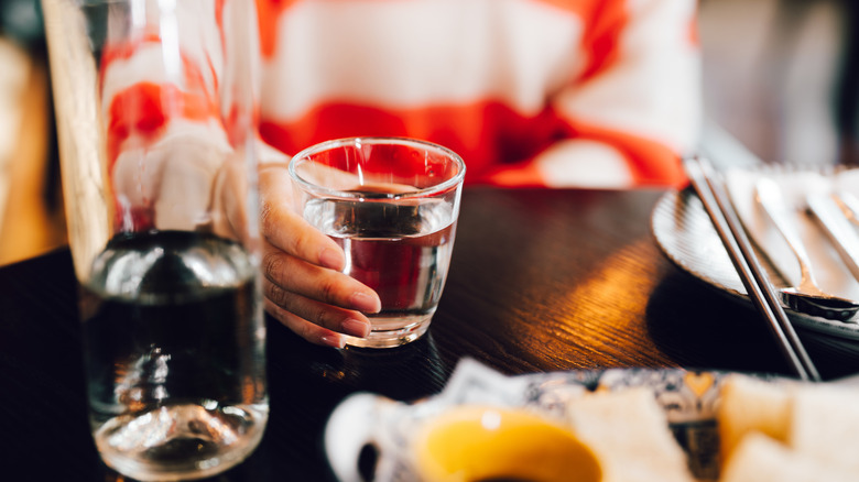 A woman's hand holding a glass of water on a restaurant table