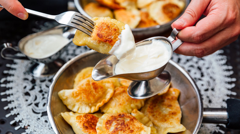 A plate of pierogies served with sour cream