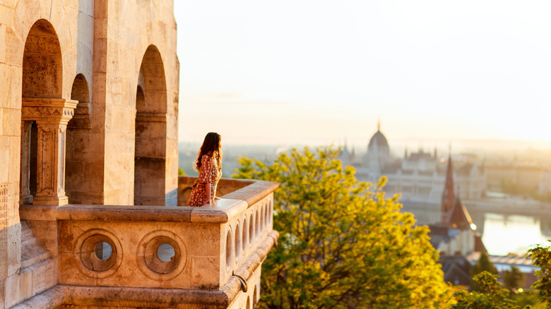 woman on stone balcony overlooking big city