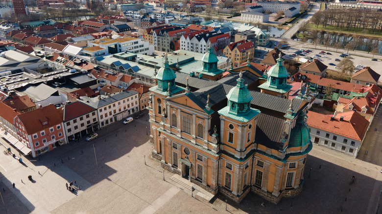 An aerial shot of the yellow Kalmar Cathedral in a downtown square