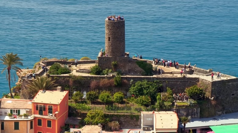 An aerial view of tourists visiting a castle and tower in Cinque Terre.