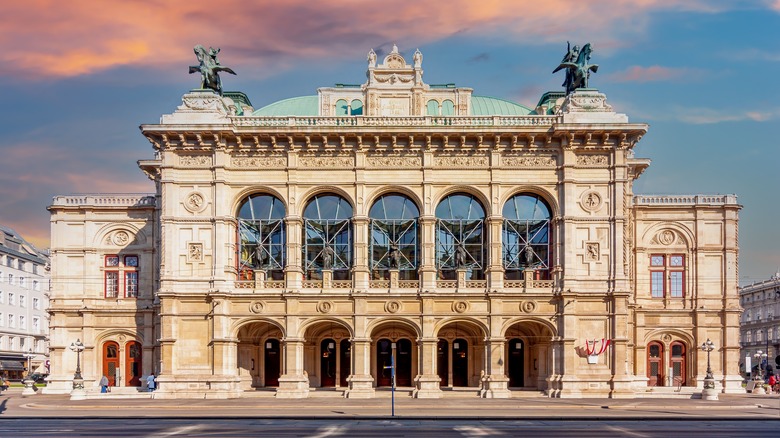 Grand building with rooftop statues at sunset