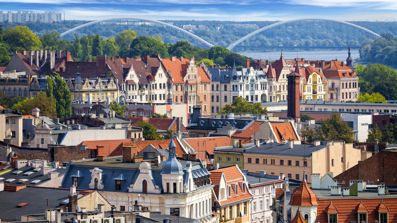 Layers of colorful buildings in Torun, with red roofs and the river in the distance