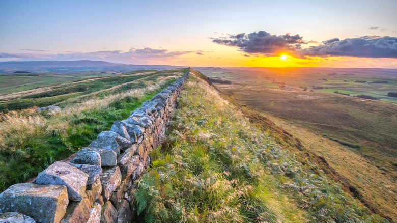 Hadrian's Wall on top of a high ridge with the setting sun in the distance