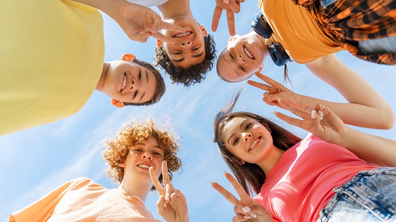 Young people posing making the peace sign hand gesture