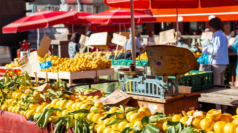Fruit on display outside on a table under red umbrellas