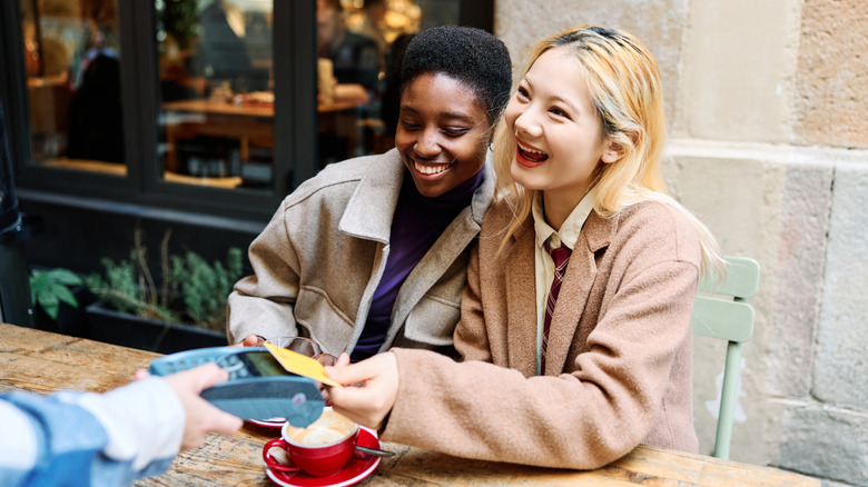 Smiling travelers paying at a restaurant
