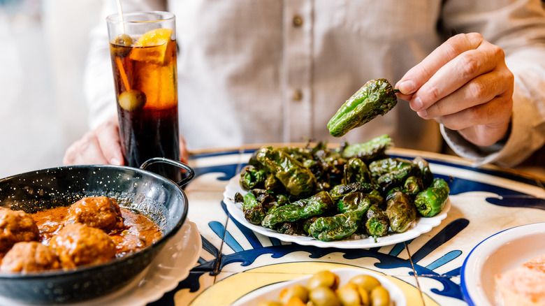 A table with grilled peppers, olives, Spanish meatballs, and vermouth