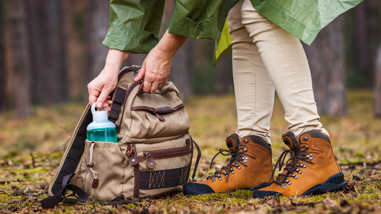 A person reaching into a backpack grabbing a water bottle
