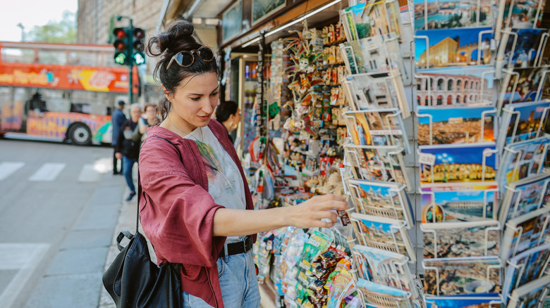 Woman shopping at a tourist shop in Verona, looking at souvenirs and postcards