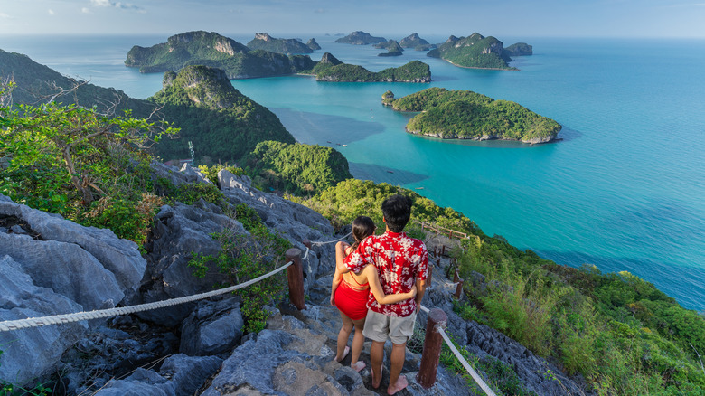 Couple at the top of a trail leading to green islands and blue sea