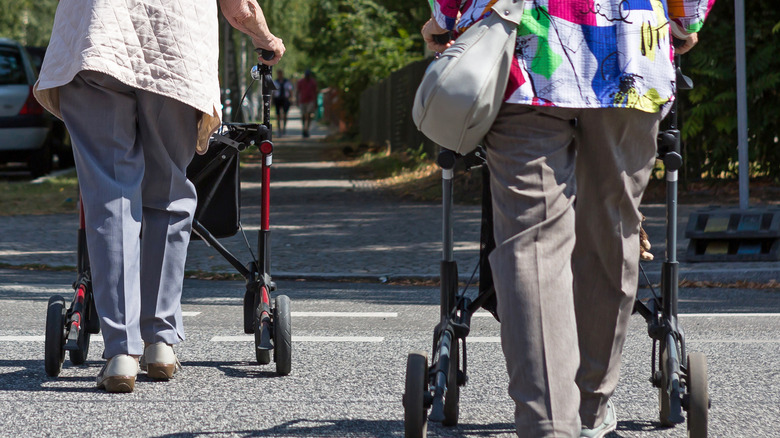 Two older women using a crosswalk with walkers
