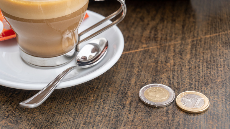 A coffee with two Euro coins placed on a table.