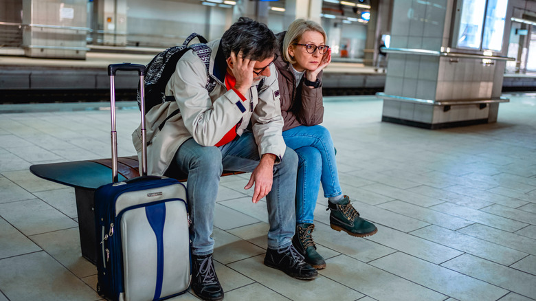 A bummed-out couple at a train stop.