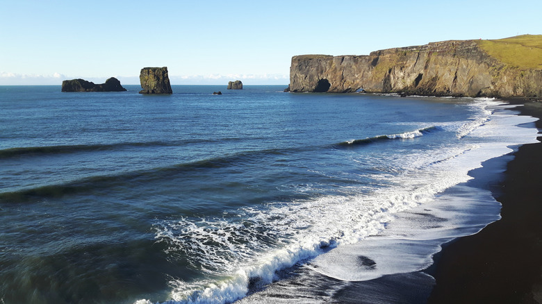 A black sand beach in Iceland with rock formations in the background