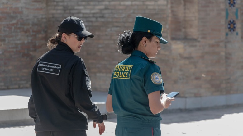 Two women dressed in tourist police authority uniforms walking in the street