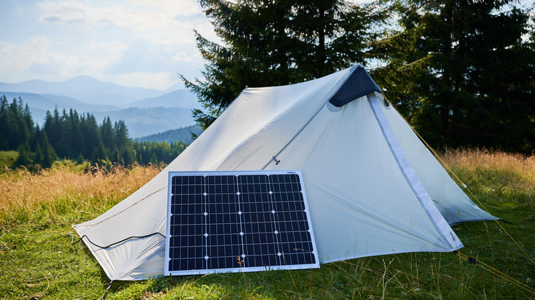 A camping tent with a solar panel outside of it.