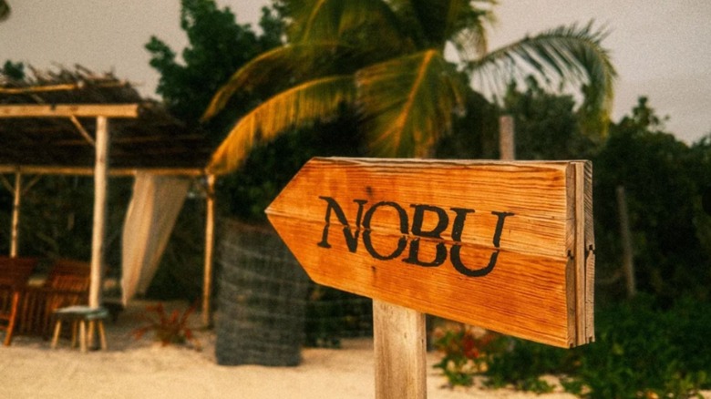 A wooden sign showing the way to Nobu Barbuda restaurant.