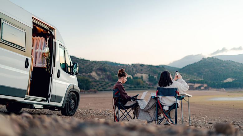 two people sitting in chairs outside of camper van