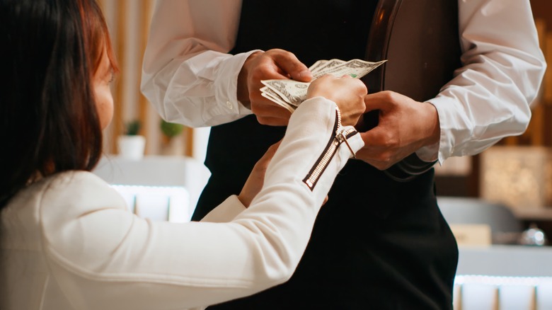 woman handing cash tip to hotel porter