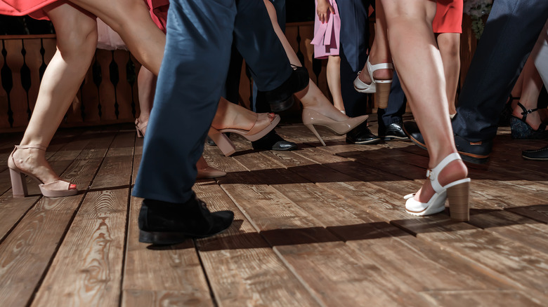 The feet of several people dancing swing jazz on wooden floorboards