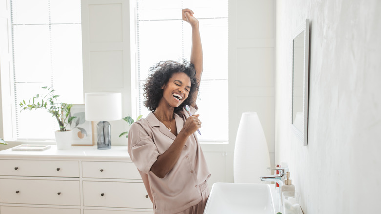 happy woman singing into toothbrush