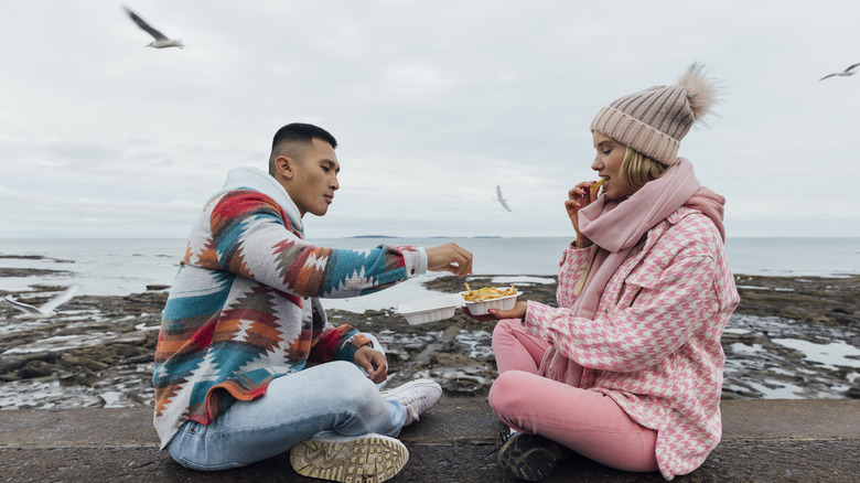 Couple enjoying meal while seagulls fly nearby