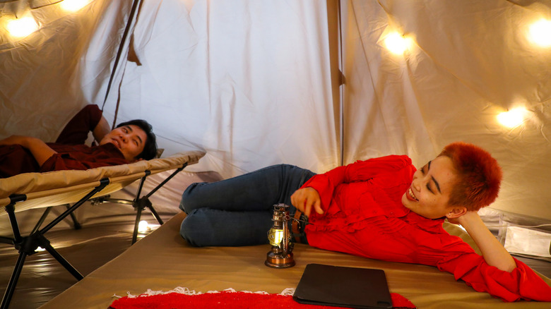 A man and woman lying down inside a tent while camping.